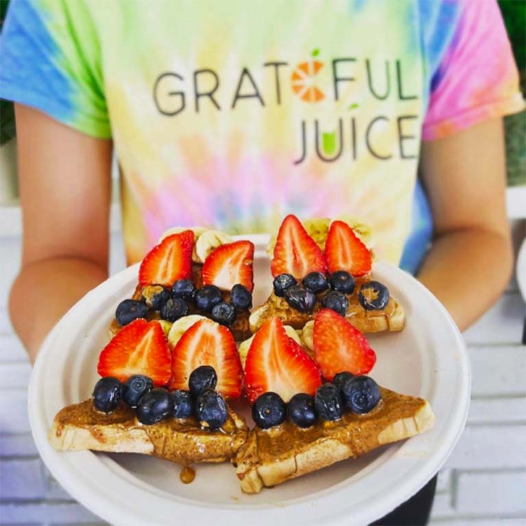 A plate of toast with peanut butter, strawberries, and blueberries.